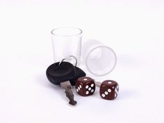 two dices are next to a shot glass with a keychain on it