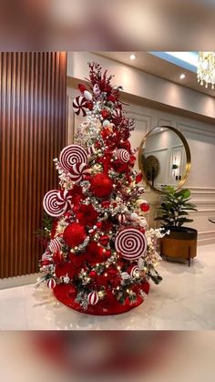 a christmas tree decorated with red and white candy canes, ornaments and decorations in a hotel lobby