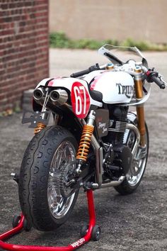 a white and red motorcycle parked on top of a parking lot next to a brick building