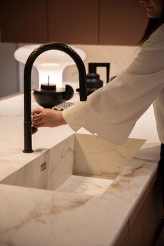 a woman is washing her hands in a sink with a faucet and soap dispenser