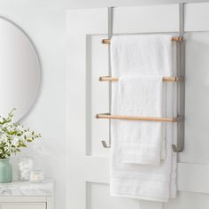 a towel rack is hanging on the wall next to a mirror and vase with flowers