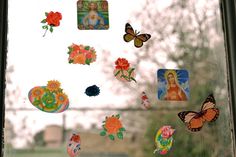 there are many stickers on the window and one is painted with flowers, butterflies, and pictures