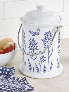 a blue and white canister sitting on top of a counter next to a bowl of fruit