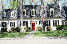 a white house with black shutters and red door