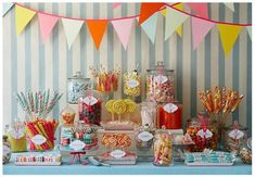 an assortment of candy and candies displayed on a table in front of striped wallpaper