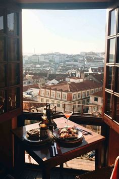 two plates of food on a table overlooking a cityscape from an open window