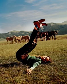 a man laying on the ground with horses in the backgroung behind him