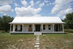 a small white house sitting in the middle of a field with steps leading up to it