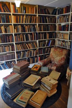 a living room filled with lots of books on top of a table next to a chair