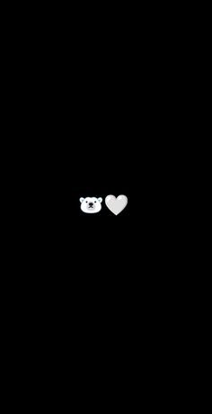 two white teddy bears sitting next to each other on a black background with hearts in the dark