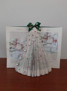 an origami christmas tree made out of book pages on a table with a green bow