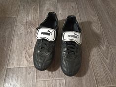 a pair of black puma sneakers on a wood floor with white and black trim