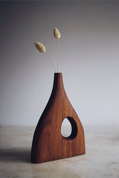 a wooden vase with two dried flowers in it