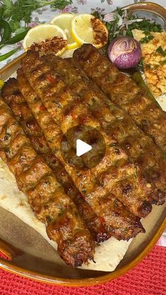 a plate with some meat on it and other food items next to it in front of a red table cloth