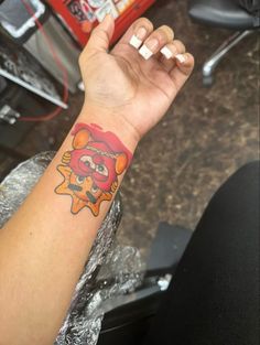 a person with a red and yellow tattoo on their arm holding something in the air