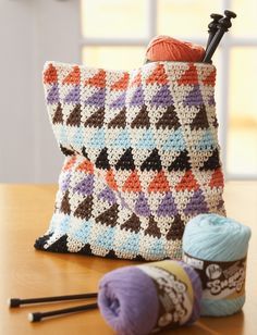 a crocheted bag sitting on top of a wooden table next to a ball of yarn