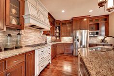 a large kitchen with wooden cabinets and marble counter tops, along with stainless steel appliances