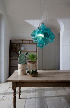 a wooden table topped with potted plants next to a light hanging from the ceiling