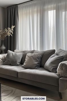 a living room filled with lots of furniture next to a window covered in white curtains