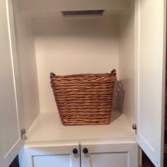 a basket is sitting on top of a white cabinet in the corner of a room