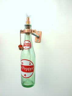 a green bottle hanging from a hook on a wall with the word peppee written on it