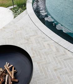 a fire pit sitting on top of a patio next to a swimming pool