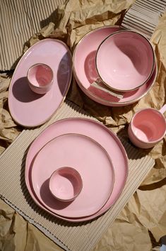 pink plates and cups are sitting on brown paper