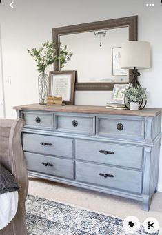 an old dresser is painted blue and has flowers on it, along with a framed mirror