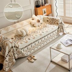 a living room with a couch covered in a blanket and pillows next to a coffee table