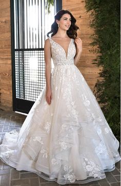 a woman in a white wedding dress standing next to a wall with greenery on it