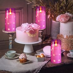 pink candles are lit on top of cakes and cupcakes, with flowers in the background