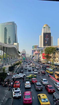 a busy city street filled with lots of traffic and tall buildings in the back ground