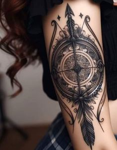 a woman's thigh with an arrow and compass tattoo on it