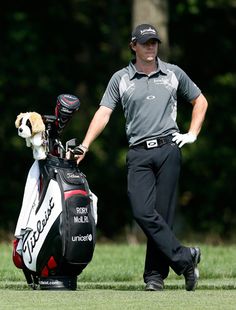 a man holding a golf bag with a dog on top of it next to him