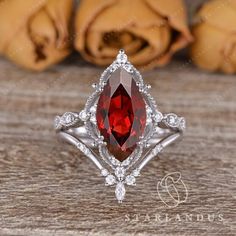 a close up of a ring with a red stone in the center on a wooden surface