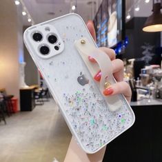 a woman holding up an iphone case with glitters on it and a phone holder in her hand