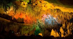 an image of the inside of a cave with colorful lights and water flowing from it