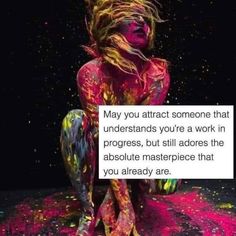 a woman sitting on the ground covered in colored powder with her hands behind her back