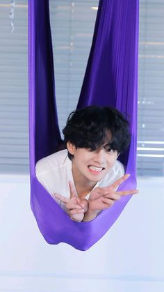 a person in a purple hammock with one hand up