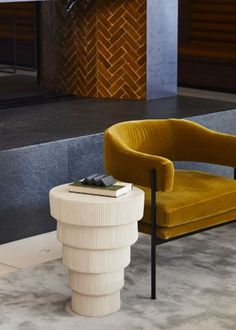 a yellow chair sitting next to a table with a book on it's side