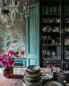 a table topped with lots of plates next to a vase filled with flowers and glasses