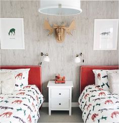 two beds in a room with pictures on the wall and one bed has a red headboard