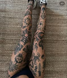 a person with many tattoos on their legs and feet, sitting on the floor next to a rug