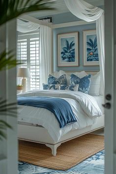 a bedroom with blue walls and white bedding, framed pictures on the wall above the bed