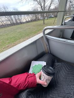 a person holding a cup of coffee while sitting in the back of a truck