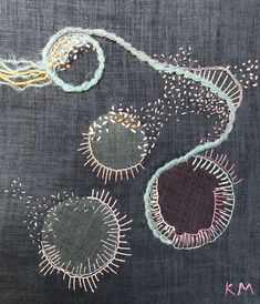 an embroidered piece of cloth with various stitches and threads on the fabric, including two circles