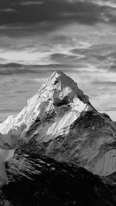 black and white photograph of the top of a snow - capped mountain with clouds in the background