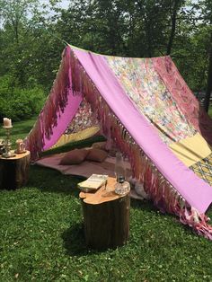 a pink and yellow tent sitting on top of a lush green field next to trees