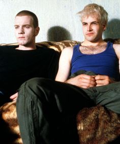 two men sitting on a couch with their arms crossed