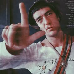 a young man is making the peace sign with his hand while wearing a baseball cap